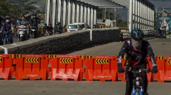 Sejumlah pengendara melintas pada sisi jalur Jembatan Sungai Citarum yang ditutup di Jalan Raya Dayeuhkolot, Kabupaten Bandung, Jawa Barat, Minggu (25/7/2021).  ANTARA FOTO/Novrian Arbi