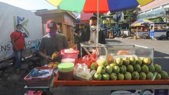 Pedagang kaki lima melayani pembeli di sekitar kawasan Sudirman, Jakarta Pusat, Senin (26/7/2021). [Suara.com/Alfian Winanto]