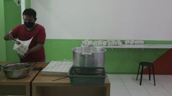 Pekerja membungkus makanan di Wartegan, Ampera, Jakarta, Senin (26/7/2021). [Suara.com/Angga Budhiyanto]