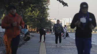 Warga berolahraga di kawasan Danau Sunter, Jakarta, Selasa (27/7/2021). [Suara.com/Angga Budhiyanto]