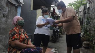 Warga menandatangani bukti penerimaan bantuan sosial non tunai berupa beras di RW 03 Kelurahan Tanah Tinggi, Kecamatan Johar Baru, Jakarta, Kamis (29/7/2021). [Suara.com/Angga Budhiyanto]