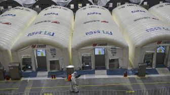 Petugas menyemprotkan disinfektan di laboratorium unit laboratorium "Mata Api" sementara yang digunakan untuk pengujian COVID-19 di sebuah pusat pameran di Nanjing, Provinsi Jiangsu, China, pada (28/7/2021). [STR / AFP]