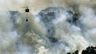 Helikopter tentara Lebanon menjatuhkan air pada kebakaran hutan di daerah Qubayyat di wilayah terpencil Akkar, Lebanon, pada (29/7/2021). [JOSEPH EID / AFP]