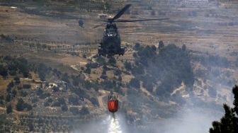 Helikopter tentara Lebanon menjatuhkan air pada kebakaran hutan di daerah Qubayyat di wilayah terpencil Akkar, Lebanon, pada (29/7/2021). [JOSEPH EID / AFP]