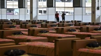 Pekerja menyiapkan kasur dan selimut untuk tempat tidur kardus di rumah sakit lapangan COVID-19 di dalam gudang Bandara Internasional Don Mueang, Bangkok, Thailand, pada (27/7/2021). [Lillian SUWANRUMPHA / AFP]