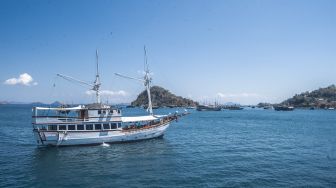 Sebuah kapal wisata pinisi melintas di perairan dekat Dermaga Labuan Bajo, Manggarai Barat, Nusa Tenggara Timur, Jumat (30/7/2021). [ANTARA FOTO/Muhammad Adimaja]