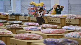 Pekerja menyiapkan kasur dan selimut untuk tempat tidur kardus di rumah sakit lapangan COVID-19 di dalam gudang Bandara Internasional Don Mueang, Bangkok, Thailand, pada (27/7/2021). [Lillian SUWANRUMPHA / AFP]