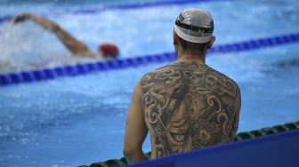 Tato di punggung seorang perenang terlihat sebelum acara renang selama Olimpiade Tokyo 2020 di Tokyo Aquatics Center, Tokyo, pada (29/7/2021). [Oli SCARFF / AFP]