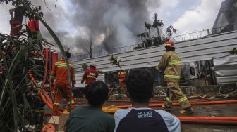 Warga melihat petugas pemadam kebakaran saat memadamkan api yang membakar gudang alat pesta di Kawasan Cinangka, Depok, Jawa Barat, Senin (2/8/2021). ANTARA FOTO/Asprilla Dwi Adha