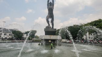 Petugas Dinas Pertamanan dan Kehutanan DKI Jakarta melakukan perwatan rutin kolam air mancur Patung Pemuda Membangun di Bundaran Senayan, Jakarta Pusat, Senin (2/8/2021). [Suara.com/Alfian Winanto]