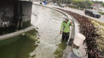 Petugas Dinas Pertamanan dan Kehutanan DKI Jakarta membersihkan bagian dasar kolam air mancur Patung Pemuda Membangun di Bundaran Senayan, Jakarta Pusat, Senin (2/8/2021). [Suara.com/Alfian Winanto]