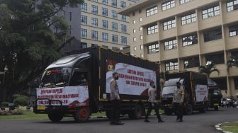 Petugas kepolisian berdiri di dekat truk yang membawa bantuan 1.000 oksigen konsentrator untuk warga yang terpapar COVID-19 di Mabes Polri, Jakarta, Selasa (3/8/2021). [Suara.com/Angga Budhiyanto] 