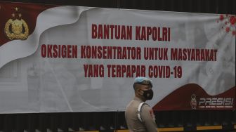 Petugas kepolisian berdiri di dekat truk yang membawa bantuan 1.000 oksigen konsentrator untuk warga yang terpapar COVID-19 di Mabes Polri, Jakarta, Selasa (3/8/2021). [Suara.com/Angga Budhiyanto] 