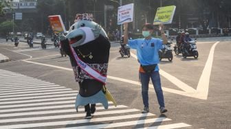 Maskot Hari Konsumen Nasional (Harkonas) Si Enda melakukan aksi kampanye kepada pengendara di kawasan Tugu Tani, Jakarta Pusat, Selasa (3/8/2021). [Suara.com/Alfian Winanto]