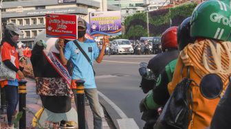 Maskot Hari Konsumen Nasional (Harkonas) Si Enda melakukan aksi kampanye kepada pengendara di kawasan Tugu Tani, Jakarta Pusat, Selasa (3/8/2021). [Suara.com/Alfian Winanto]