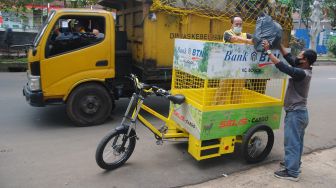 Petugas Dinas Lingkungan Hidup (DLH) Kota Bogor memasukkan sampah kedalam sepeda listrik pengangkut sampah di jalan Paledang, Kota Bogor, Jawa Barat, Rabu (4/8/2021). ANTARA FOTO/Arif Firmansyah