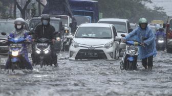 Pengendara mendorong sepeda motor yang mogok saat melintasi genangan air di Jalan Margonda Raya, Depok, Jawa Barat, Kamis (5/8/2021).  ANTARA FOTO/Asprilla Dwi Adha