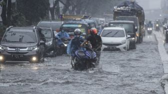 Pengendara mendorong sepeda motor yang mogok saat melintasi genangan air di Jalan Margonda Raya, Depok, Jawa Barat, Kamis (5/8/2021).  ANTARA FOTO/Asprilla Dwi Adha