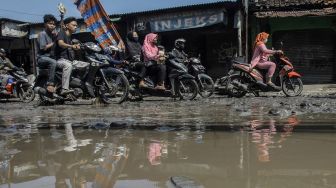 Pengendara melintasi jalan penghubung antara Kabupaten Bogor dan Kota Depok yang rusak di Pabuaran, Kabupaten Bogor, Jawa Barat, Jumat (6/8/2021).  ANTARA FOTO/Yulius Satria Wijaya
