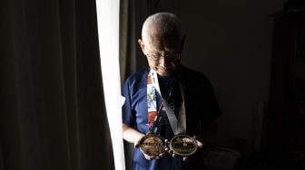 Ironman tertua di dunia Hiromu Inada (88) memegang dua medali dari Kejuaraan Dunia Ironman, perlombaan triathlon tahunan di Hawaii, di rumahnya, di Inage, Chiba Prefektur, Jepang, pada (2/8/2021). [Yuki IWAMURA / AFP]