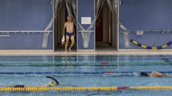 Ironman tertua di dunia Hiromu Inada (88) berjalan ke kolam renang di Sekolah Renang Internasional Inage, Inage, Chiba Prefektur, Jepang, pada (2/8/2021). [Yuki IWAMURA / AFP]