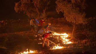 Warga mencoba memadamkan api yang menyebar di desa Akcayaka, Milas, Provinsi Mugla, Turki, pada (6/8/2021). [Yasin AKGUL / AFP]