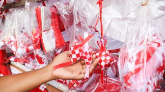 Pedagang menunjukkan pernak-pernik bendera merah putih yang dijualnya di Jalan Matraman Raya, Jatinegara, Jakarta Timur, Minggu (8/8/2021). [Suara.com/Alfian Winanto]