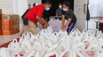  Petugas bersiap mendistribusikan nasi box di dapur umum Kementerian Sosial di Gedung Konvensi, Taman Makam Pahlawan (TMP) Kalibata, Jakarta, Minggu (8/8/2021). [Suara.com/Alfian Winanto]
