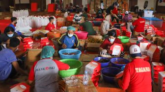 Aktivitas petugas mengemas makanan ke dalam box di dapur umum Kementerian Sosial di Gedung Konvensi, Taman Makam Pahlawan (TMP) Kalibata, Jakarta, Minggu (8/8/2021). [Suara.com/Alfian Winanto]