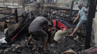 Warga mencari barang yang masih bisa digunakan pascakebakaran di kawasan Grogol Petamburan, Jakarta, Selasa (10/8/2021). [Suara.com/Angga Budhiyanto]