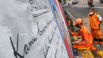 Petugas PPSU menyelesaikan pembuatan mural bertema Hari Kemerdekaan Indonesia di Fly Over Kawasan Tebet, Jakarta Selatan, Selasa (10/8/2021). [Suara.com/Alfian Winanto]