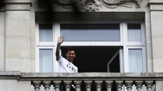 Pesepak bola Lionel Messi menyapa penggemarnya dari balkon hotel Royal Monceau, Paris, Prancis, Selasa (10/8/2021).  [AFP Photo]