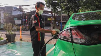 Petugas menaruh kontak tusuk ke kendaraan untuk melakukan pengisian daya di Stasiun Pengisian Kendaraan Listrik Umum (SPKLU) di Kawasan MT. Haryono, Jakarta Selatan, Rabu (11/8/2021). [Suara.com/Alfian Winanto]