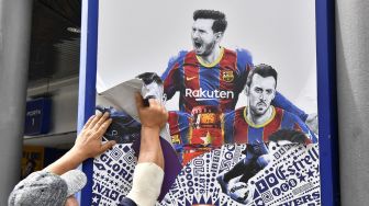 Pekerja melepas poster-poster Lionel Messi di Stadion Camp Nou, Barcelona, Spanyol, (10/8/2021).  [AFP Photo]