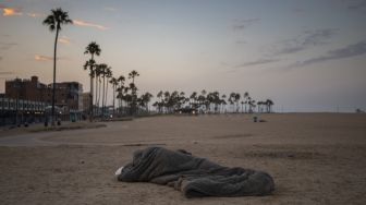 Tunawisma tidur di pantai pada pagi hari di Pantai Venesia, California, Amerika Serikat, pada (12/8/2021). [Apu GOMES / AFP]