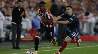 Gelandang Brentford Frank Onyeka (kiri) melewati striker Arsenal Gabriel Martinelli (kanan) selama pertandingan sepak bola Liga Premier Inggris antara Brentford dan Arsenal di Brentford Community Stadium, London, pada (13/8/2021). [Adrian DENNIS / AFP]