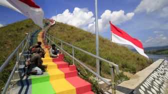 Pekerja mengecat anak tangga yang yang di dinding besinya akan dipasang bendera Merah Putih di bukit Tungku Wiri atau Bukit Teletubies, Kampung Doyo Lama, Distrik Waibu, Kabupaten Jayapura, Papua, Senin (16/8/2021). ANTARA FOTO/Gusti Tanati 
