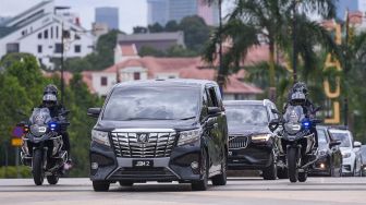 Perdana Menteri Malaysia Muhyiddin Yassin melambaikan tangannya dari dalam mobil kepada para wartawan sebelum bertemu dengan Raja Malaysia, di Istana Negara, Kuala Lumpur, Senin (16/8/2021). [AFP Photo]