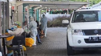 Suasana petugas melakukan swab PCR kepada warga secara drive thru di GSI Lab, Jakarta Selatan, Senin (16/8/2021). [Suara.com/Alfian Winanto]