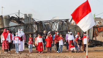 Anak-anak dari Komunitas Kelas Jurnalis Cilik melakukan upacara bendera HUT RI ke-76 di Belah Kapal, Cilincing, Jakarta Utara, Selasa (17/8/2021). [Suara.com/Alfian Winanto]