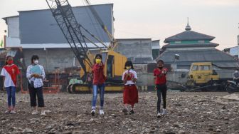 Anak-anak dari Komunitas Kelas Jurnalis Cilik melakukan upacara bendera HUT RI ke-76 di Belah Kapal, Cilincing, Jakarta Utara, Selasa (17/8/2021). [Suara.com/Alfian Winanto]