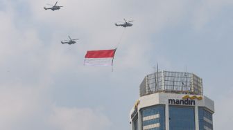 Bendera Merah Putih raksasa yang dikibarkan menggunakan helikopter TNI Angkatan Udara mengelilingi Jakarta, Selasa (13/8/2021). [Suara.com/Alfian Winanto]