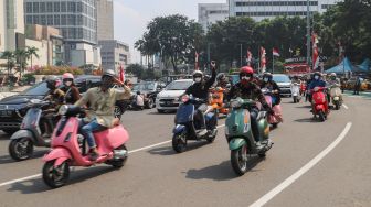 Komunitas Motor Vespa melintas di kawasan Bundaran Hotel Indonesia (HI), Jakarta Pusat, Selasa (17/8/2021). [Suara.com/Alfian Winanto]