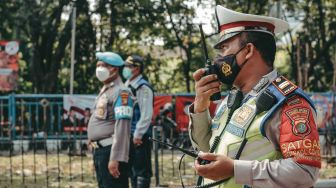 Seorang petugas kepolisian tengah menghimbau warga untuk turun sejenak dari kendaraan roda dua dan bersikap sempurna di Tugu TMP, Kota Tangerang Selasa 17 Agustus 2021. [Suara.com/ Hilal Rauda Fiqry]