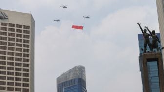 Bendera Merah Putih raksasa yang dikibarkan menggunakan helikopter TNI Angkatan Udara mengelilingi Jakarta, Selasa (13/8/2021). [Suara.com/Alfian Winanto]