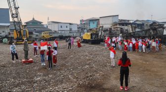 Anak-anak dari Komunitas Kelas Jurnalis Cilik melakukan upacara bendera HUT RI ke-76 di Belah Kapal, Cilincing, Jakarta Utara, Selasa (17/8/2021). [Suara.com/Alfian Winanto]