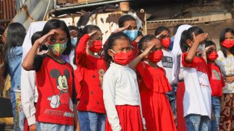 Anak-anak dari Komunitas Kelas Jurnalis Cilik melakukan upacara bendera HUT RI ke-76 di Belah Kapal, Cilincing, Jakarta Utara, Selasa (17/8/2021). [Suara.com/Alfian Winanto]