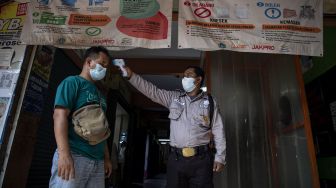 Petugas keamanan memeriksa suhu pengunjung di Pasar Muara Karang, Penjaringan, Jakarta Utara, Jumat (20/8/2021). ANTARA FOTO/Sigid Kurniawan