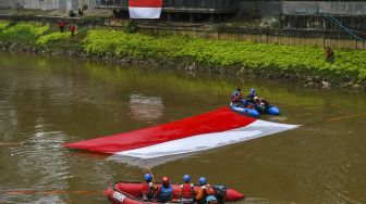 Gabungan relawan rescue membentangkan bendera Merah Putih ukuran 10x5 meter di Kali Ciliwung, Jakarta, Minggu (22/8/2021). [ANTARA FOTO/Galih Pradipta]