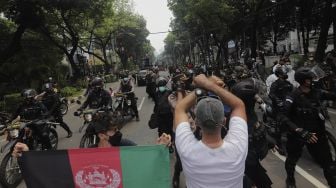 Petugas kepolisian membubarkan paksa pengungsi Afghanistan yang menggelar aksi unjuk rasa di depan Gedung UNHCR, Kebon Sirih, Jakarta, Selasa (24/8/2021). [Suara.com/Angga Budhiyanto]